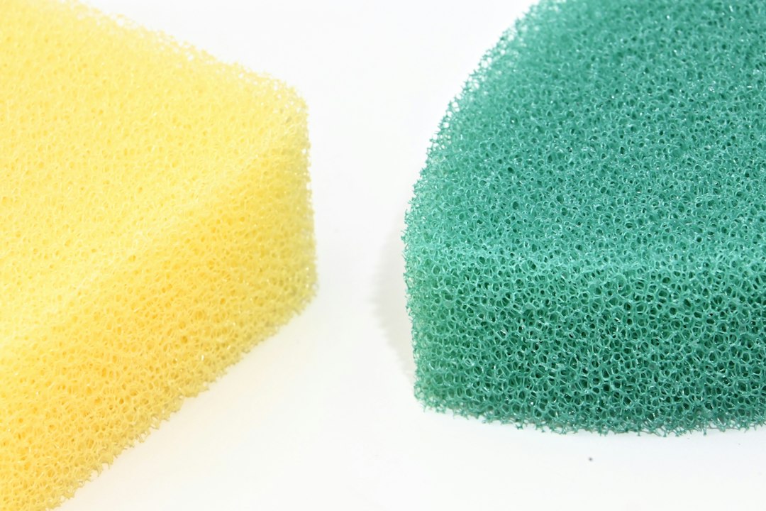Yellow and green cleaning sponges on a white surface