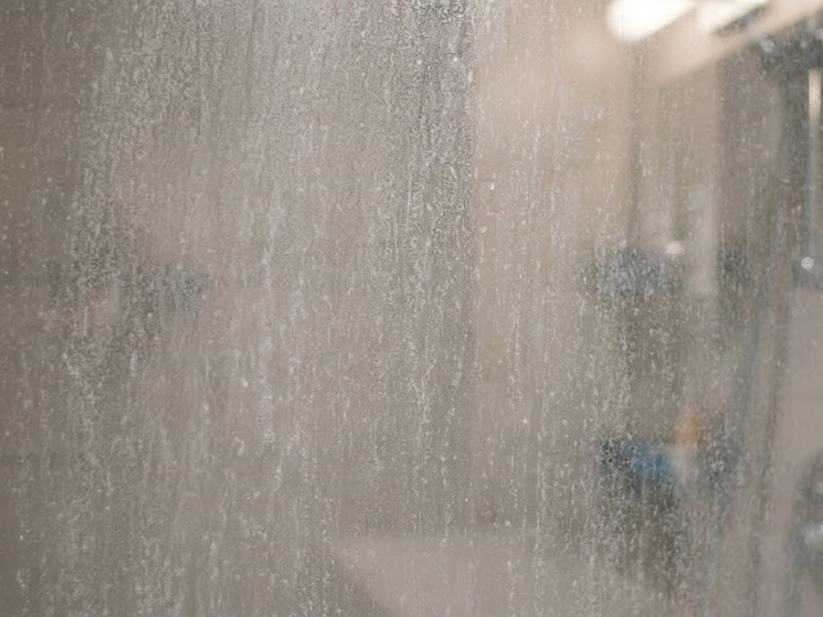 severely cloudy glass shower door with hard water stains
