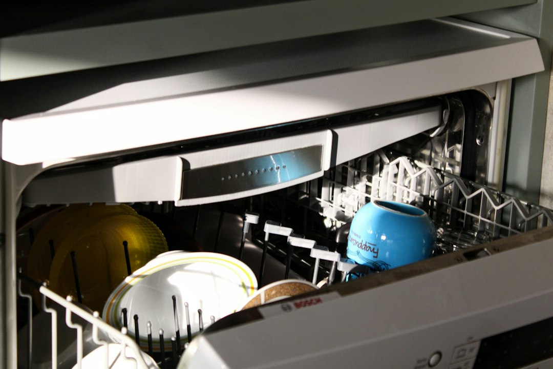 Open dishwasher containing cups and dishes