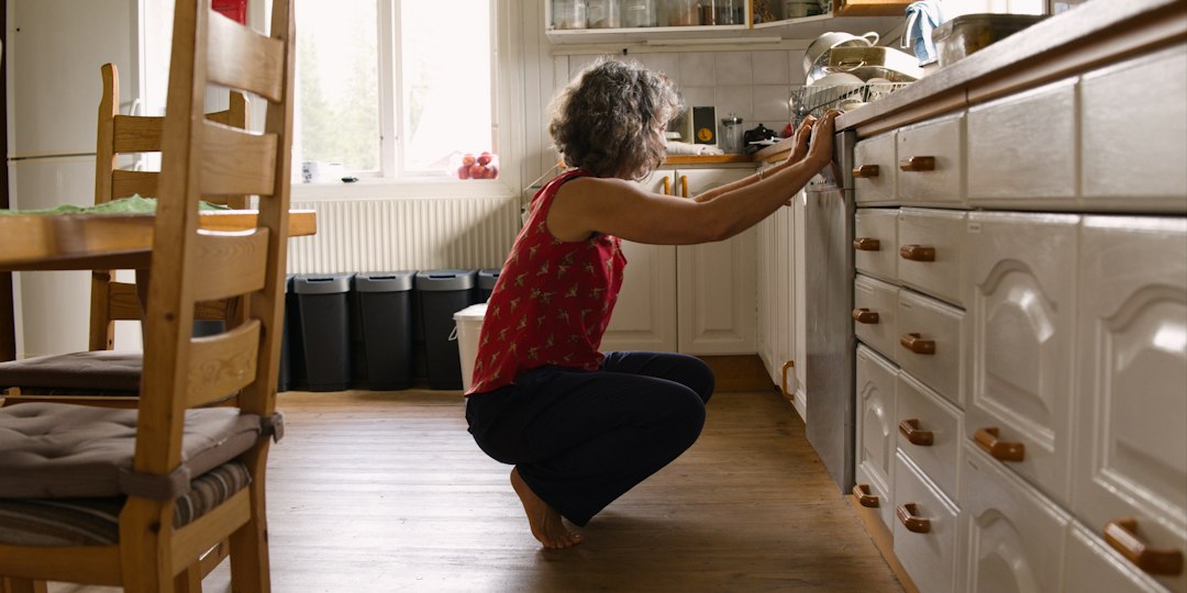 Person checking an open dishwasher in a kitchen